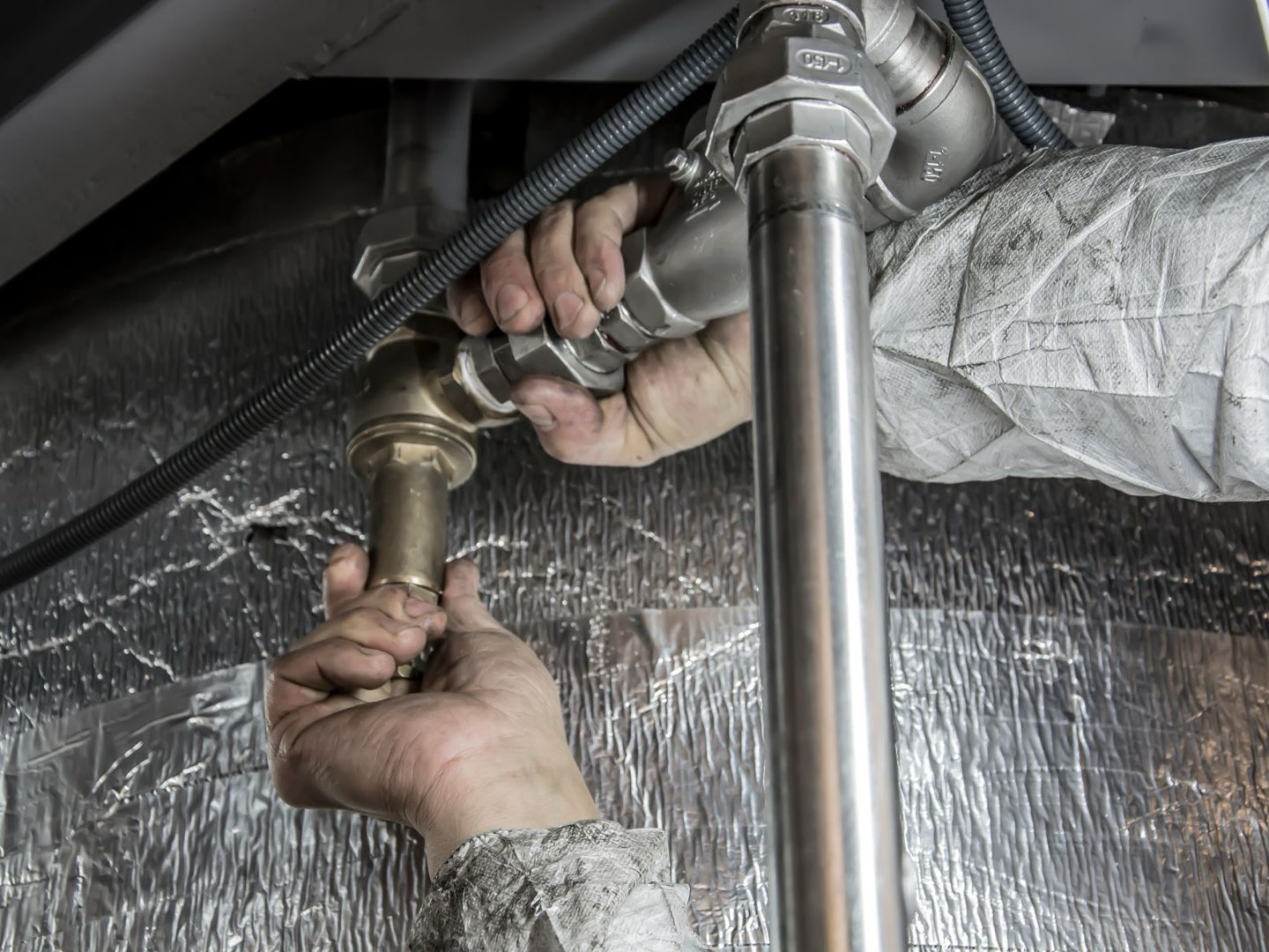 A plumber's hands fitting steel supply pipes