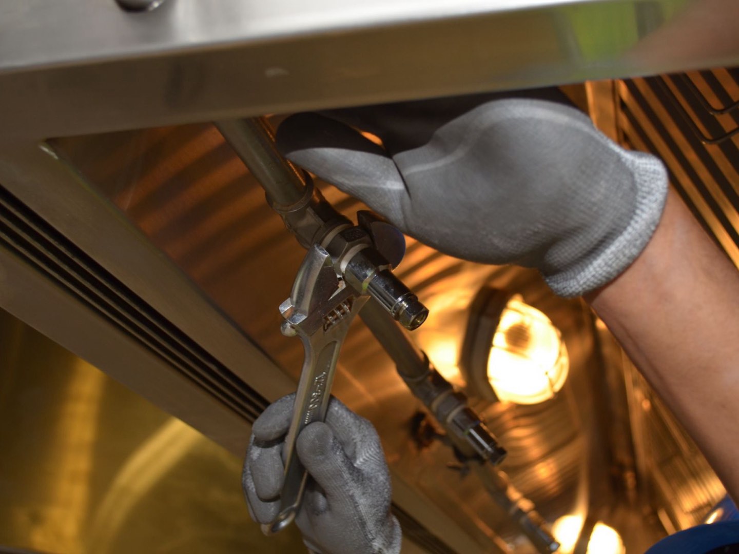 A plumber tightening a pipe fitting with a wrench