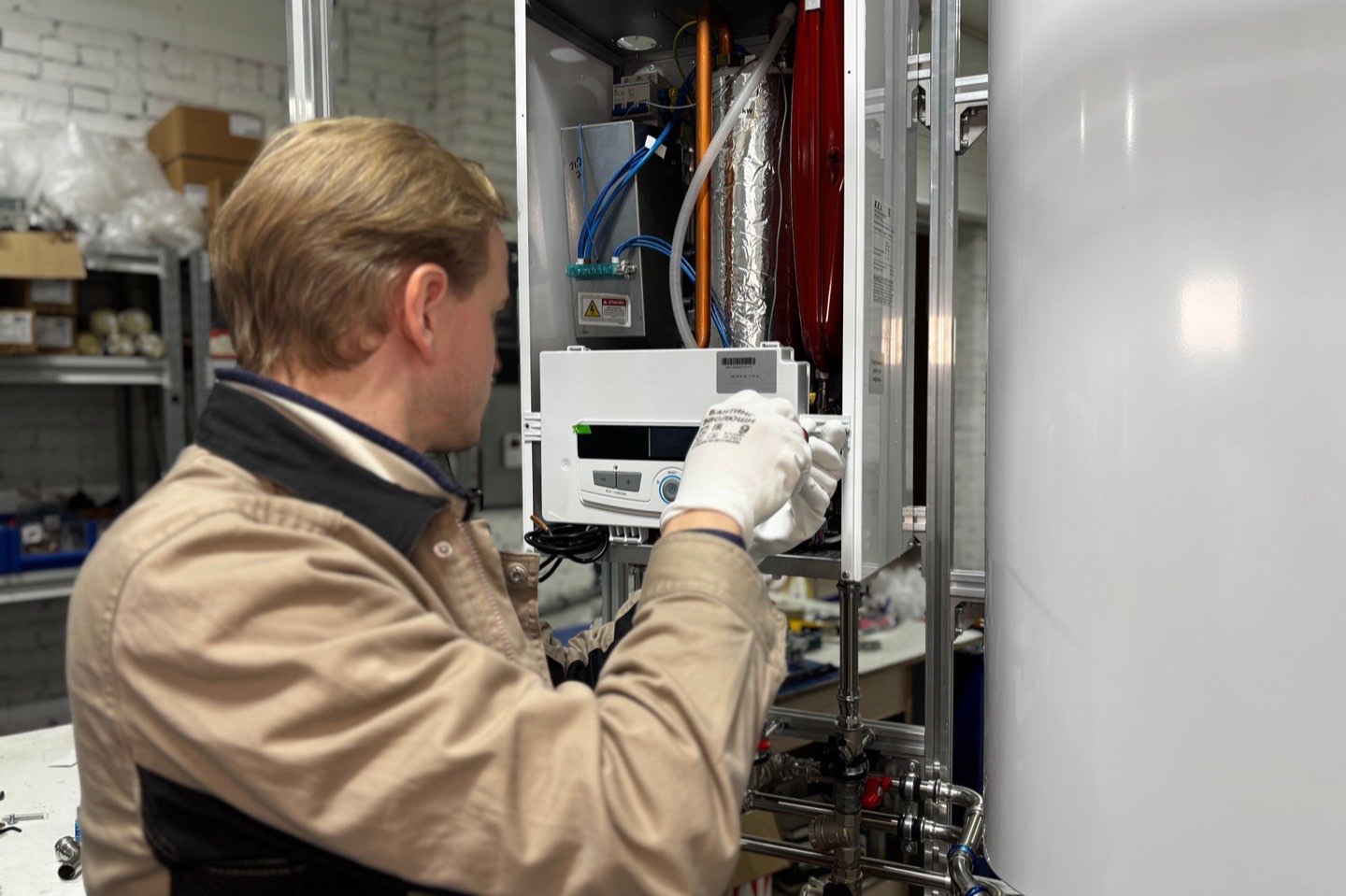 A technician servicing a wall-mounted water heater unit