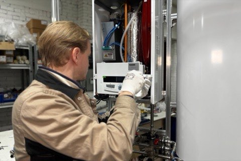 A technician servicing a wall-mounted water heater unit